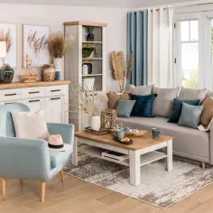 Jasny salon w stylu hampton z błękitnym fotelem, szarą kanapą i drewnianymi meblami.
