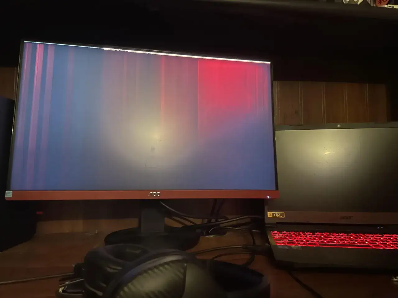 Monitor z pionowymi pasami, prawdopodobnie błąd HDCP. Jak naprawić? Obok laptop z podświetlaną klawiaturą.