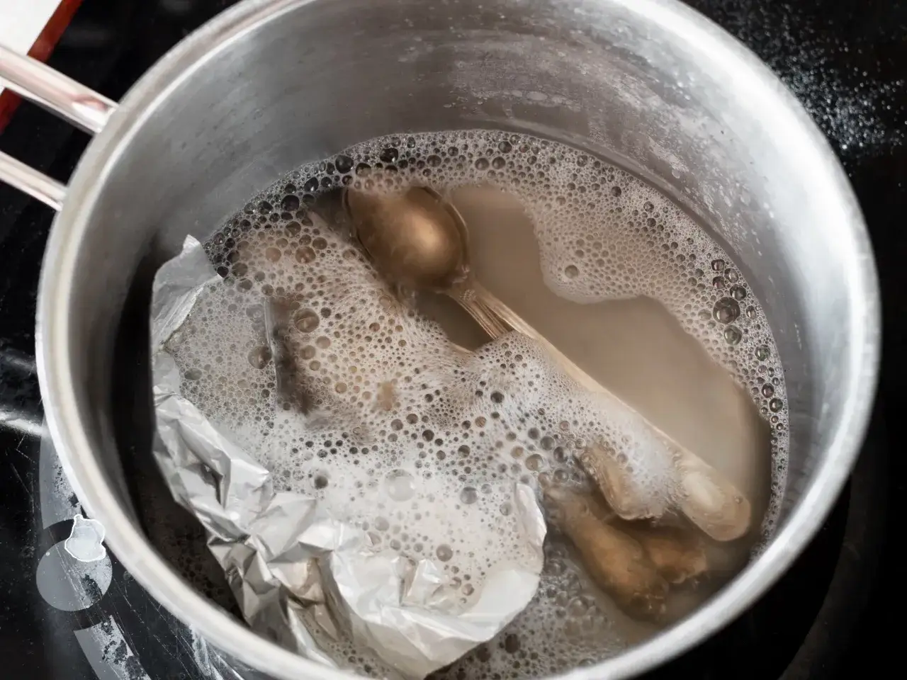 Jak wyczyścić sztućce? W garnku z wodą i folią aluminiową gotują się przyciemnione łyżeczki.