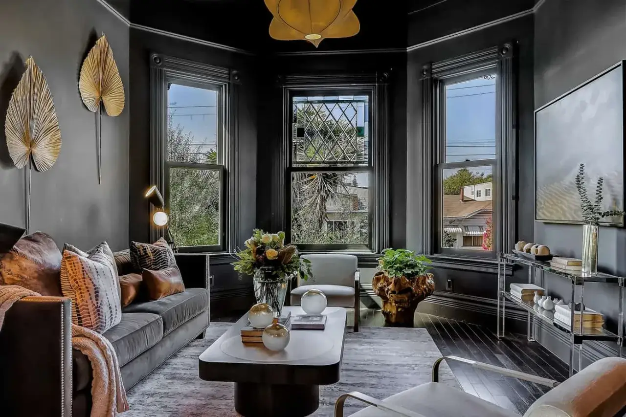 Elegancki salon w stylu wiktoriańskim z ciemnymi ścianami, wygodną sofą i ozdobnymi liśćmi na ścianie.